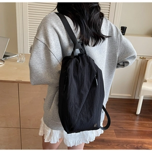Detail of black waterproof nylon crossbody bag with zipper and logo in casual setting
