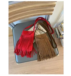 Gros plan de sacs bandoulière en daim rouge et marron avec des détails de franges rétro