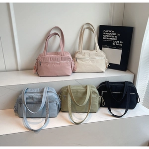 Five nylon tote bags in pastel colors arranged on steps showing wrinkled fabric detail