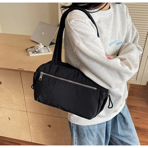 Detail of black pleated nylon tote bag with silver zipper and wide shoulder strap