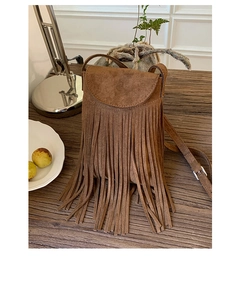 Gros plan sur un sac bandoulière en daim marron avec de longues franges et un rabat