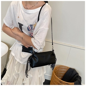 Detail of black PU fringe shoulder bag with matching mini pouch on fashion model
