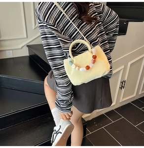 Gros plan du sac seau plissé jaune avec poignée décorative en perles de résine colorées