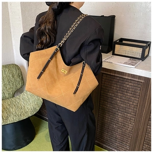 Quilted brown faux suede tote bag with gold chain strap shown on model for size and scale