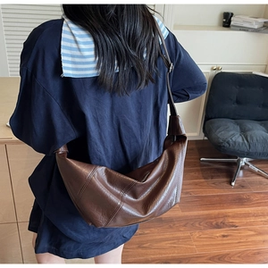Sac bandoulière demi-lune en similicuir marron porté pour illustrer la taille et le volume