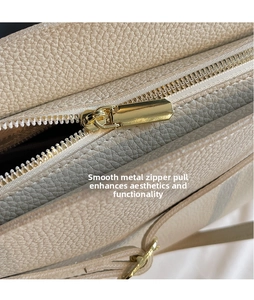 Close-up of golden metal zipper and smooth hardware on beige lychee texture leather bag