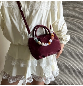 Détail du sac seau en velours bordeaux avec chaîne perlée colorée et bandoulière