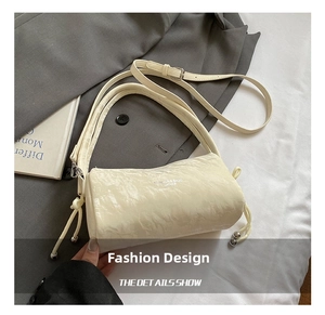 Detail of cream pleated leather cylinder bag with side drawstrings and silver beads