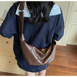 Rear view of model wearing a textured brown crescent crossbody bag in a modern room