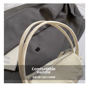 Detail of a creamy white cylindrical pillow bag featuring wrinkled patent leather texture