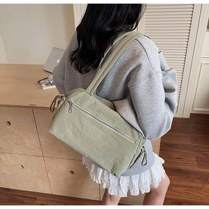 Detail of light green canvas tote bag with dual straps worn by model in a home setting