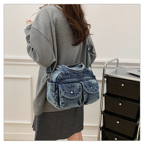 Detail of vintage denim crossbody bag featuring contrast stitching and multiple pockets