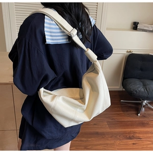 Detail of cream soft leather tote bag showing grainy texture and knotted strap buckle