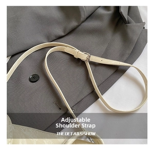 Detail of adjustable off-white leather strap with silver buckle on a gray suit fabric