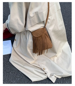 Vue de rue du sac bandoulière en daim marron avec de longues franges et une sangle