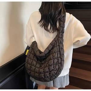 Detail of black quilted cloud bag with fashion woven label on a wooden staircase