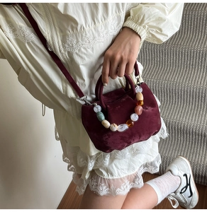 Détail du sac seau en velours bordeaux avec poignée décorative en perles de résine