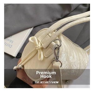 Close-up of cream white handbag featuring wrinkled texture, bow detail and silver hooks