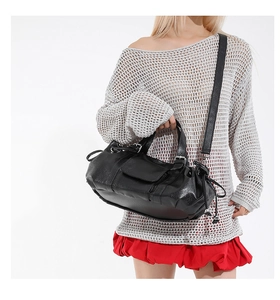 Detail of black textured leather baguette bag with drawstring side and wide shoulder strap