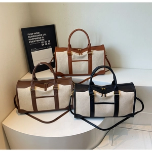 Detail view of canvas and leather travel bags in cream, brown, and black colors