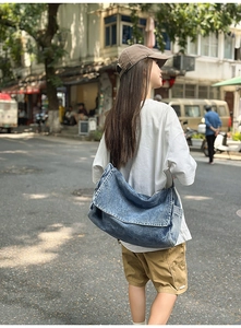 Streetstyle-Ansicht einer großen gewaschenen Denim-Umhängetasche an einem Model