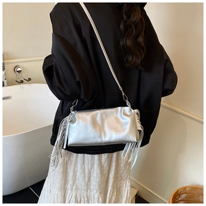 Zilveren metallic baguette tas met franjes gedragen als schoudertas in een stijlvolle setting