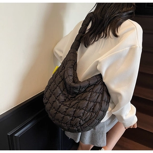 Close-up of black quilted puff bag with vibrant yellow side label and water-resistant nylon fabric