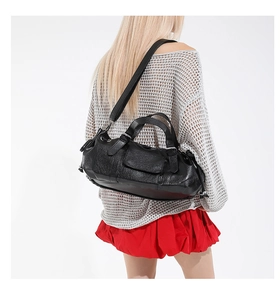 Detail of black pebbled leather shoulder bag showing texture and adjustable strap