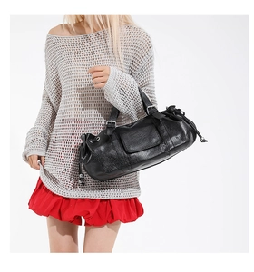Detail of black pleated leather handbag featuring silver buckle and drawstring texture