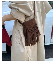 Détail d'un sac bandoulière en daim marron foncé avec de longues franges bohèmes