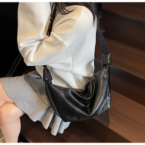 Detail of soft black leather slouchy bag with stylish knotted shoulder strap texture