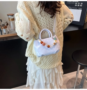 Vue portée d'un sac seau plissé lilas avec une poignée décorative en perles d'ambre