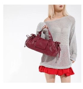 Detail of burgundy leather baguette bag with pleated sides and front flap pocket