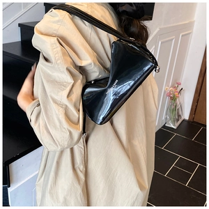 Detail of a glossy black patent leather shoulder bag with white fashion designer lettering
