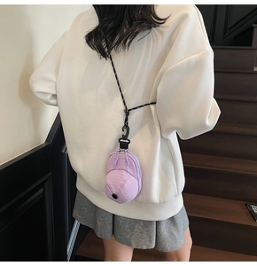 Detailed view of mini purple hat-shaped purse with textured fabric and woven lanyard