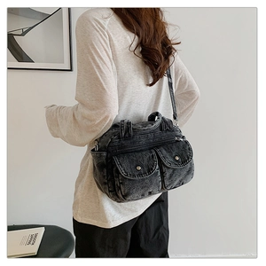 Detail of vintage washed denim crossbody bag with cargo pockets and metallic zippers