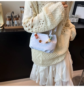 Détail du sac nuage plissé bleu clair avec une poignée en perles colorées et bandoulière