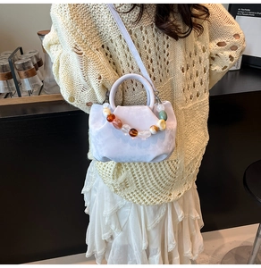 Détail du sac seau plissé lilas avec perles décoratives en résine et bandoulière fine