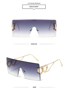 Detail view of gold metal sunglasses with double heart ornaments and gradient lenses