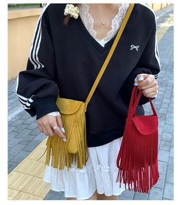 Détail de sacs bandoulière en similicuir rouge et jaune avec de longues franges