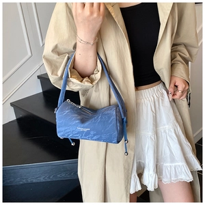 Close-up of blue cylinder pillow bag featuring natural wrinkled texture and top handles