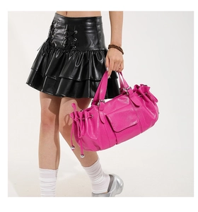 Detail of rose red pleated bag showing faux leather texture and silver buckle accents