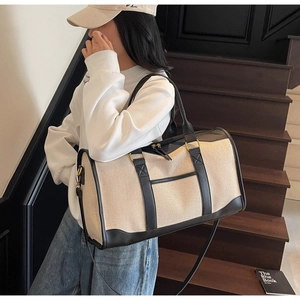 Detail of canvas travel bag with leather trim and shoulder strap shown on a model