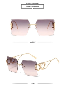 Detail view of gold rimless sunglasses with heart accents and gradient pink lenses