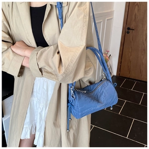 Detail of blue nylon cylinder bag featuring adjustable drawstring with silver metal beads