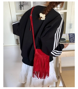 Gros plan d'un sac à bandoulière en daim rouge avec de longues franges et une fine lanière