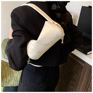 Detail view of off-white crinkled texture cylindrical crossbody bag on a black blazer
