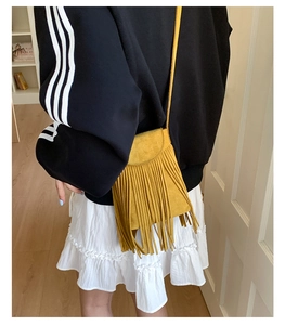 Détail d'un sac bandoulière jaune en daim avec franges au style bohème et rétro