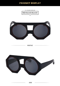 Detail of octagonal black sunglasses with red inner rim and dark grey lenses