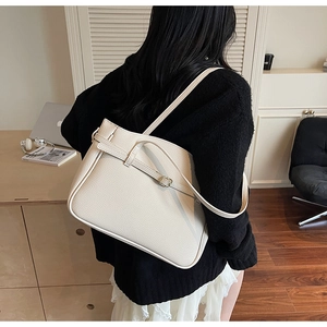 Modern creamy white tote bag with lychee texture and buckle detail worn by a model